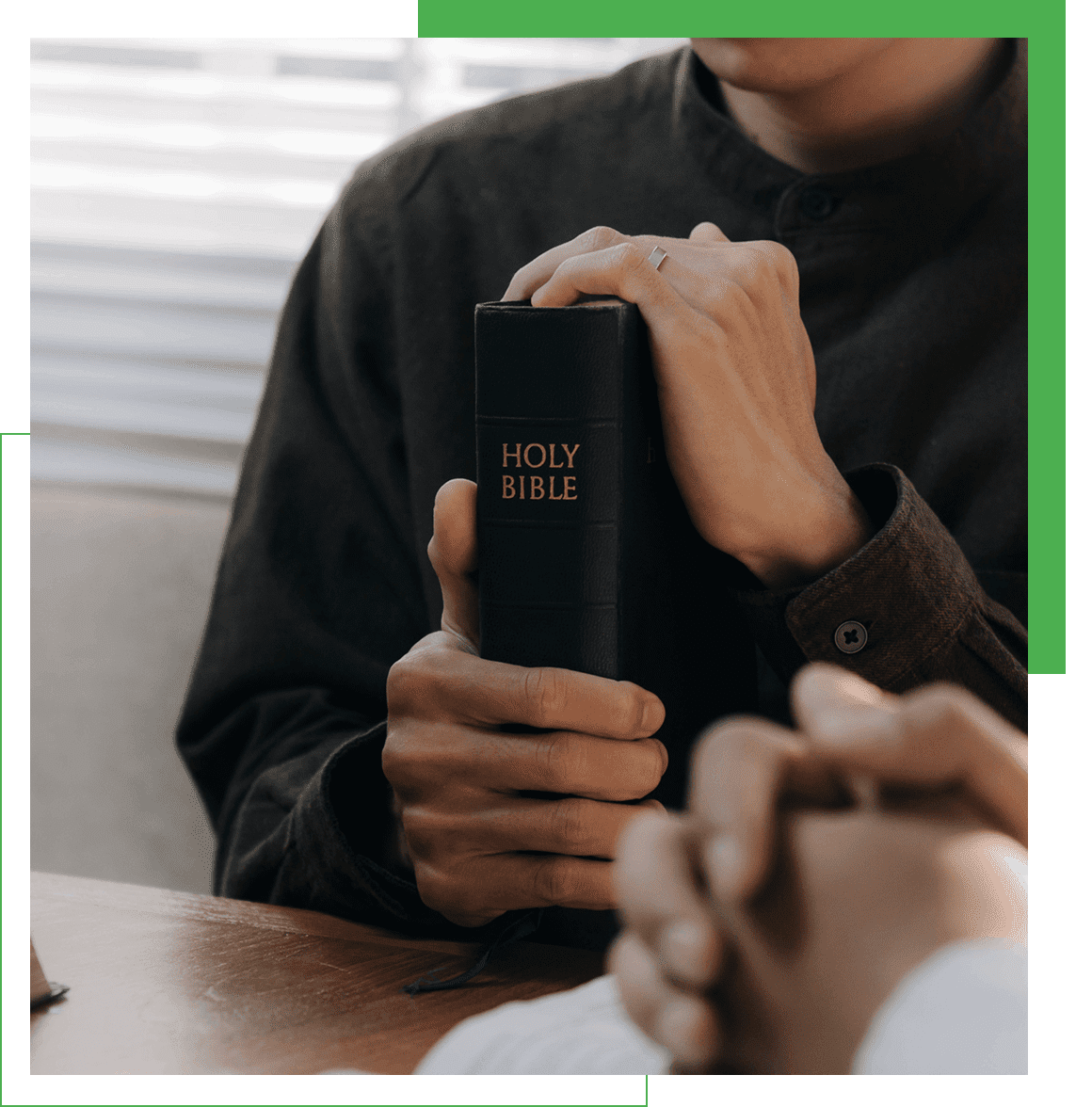 Person holding a Holy Bible, praying hands.